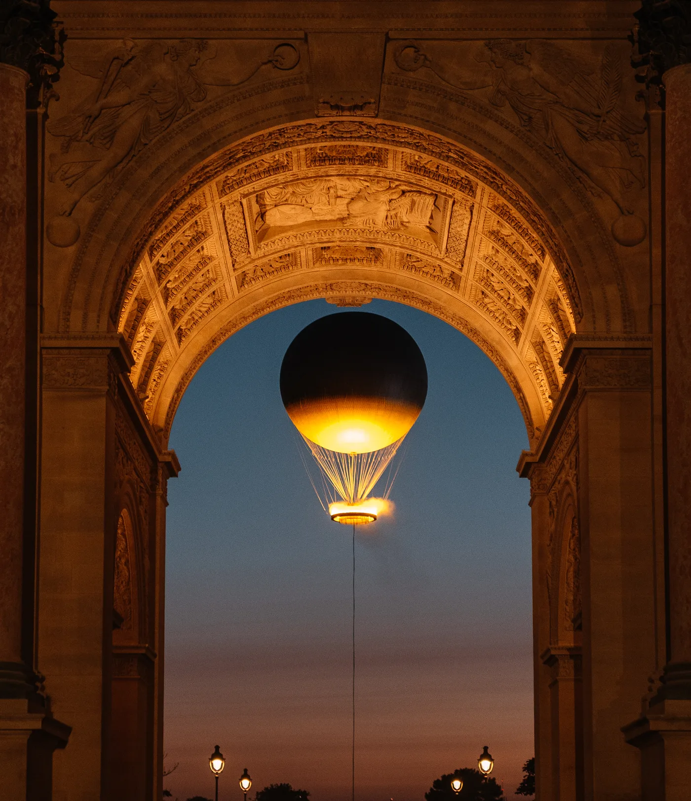 The Olympic cauldron rising above the Tuileries at dusk