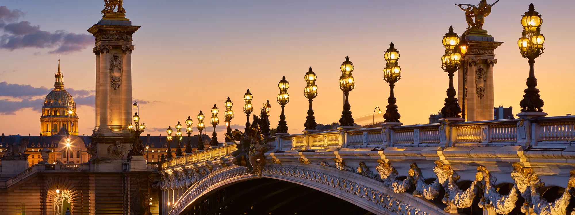 The Pont Alexandre III and its lamp posts at dusk, the dome of the Invalides in the background